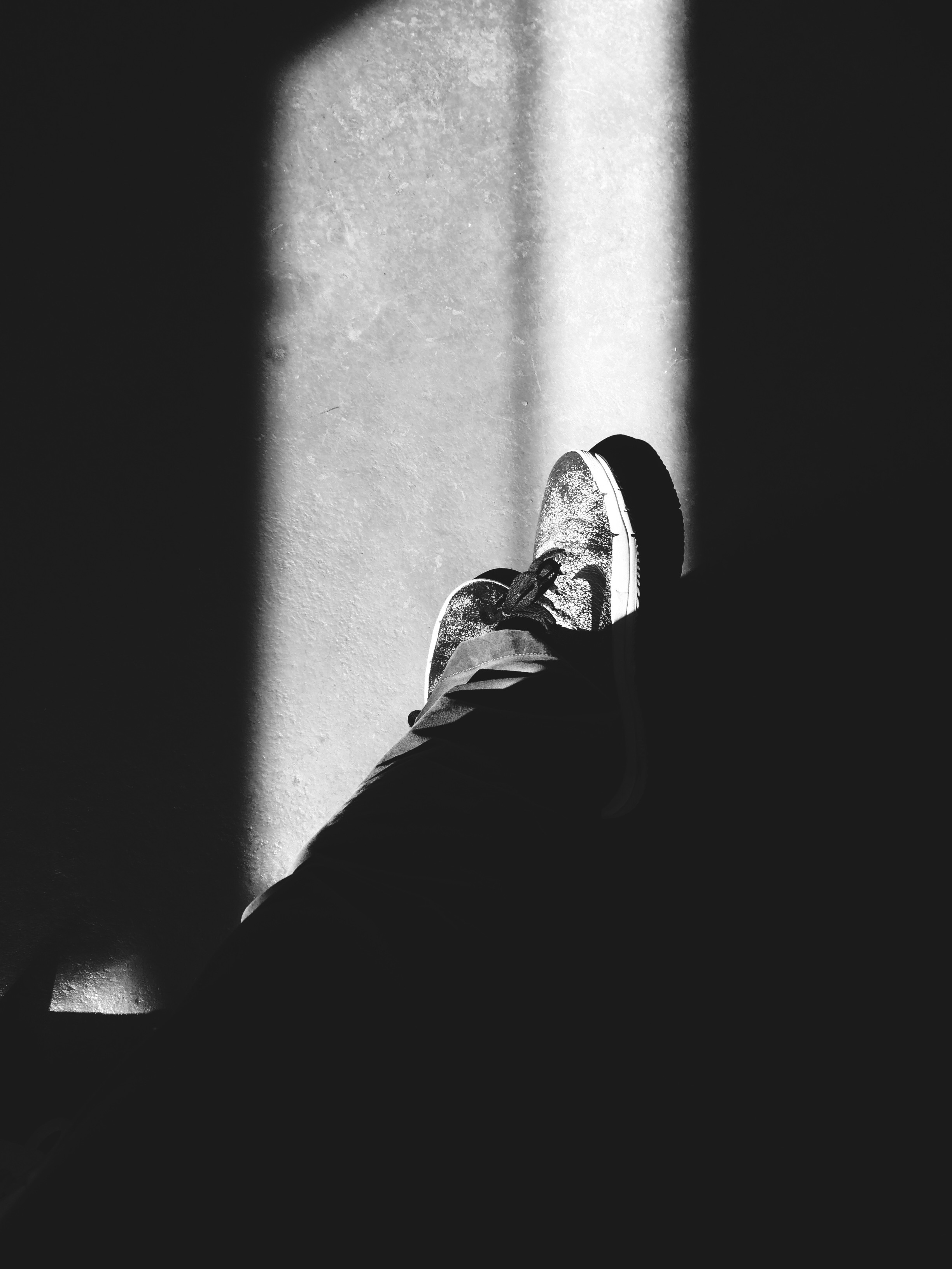 Photo looking at the floor with legs and sneakers.